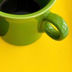 Green coffee cup on a bright yellow table