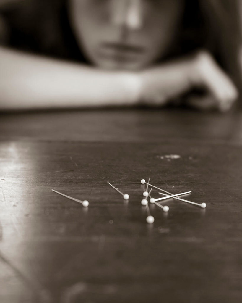 Girl watching pins on a table by Sal Taylor Kydd