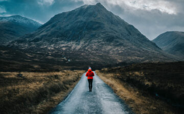 Woman walking down a road towards a mountain