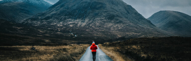 Woman walking down a road towards a mountain