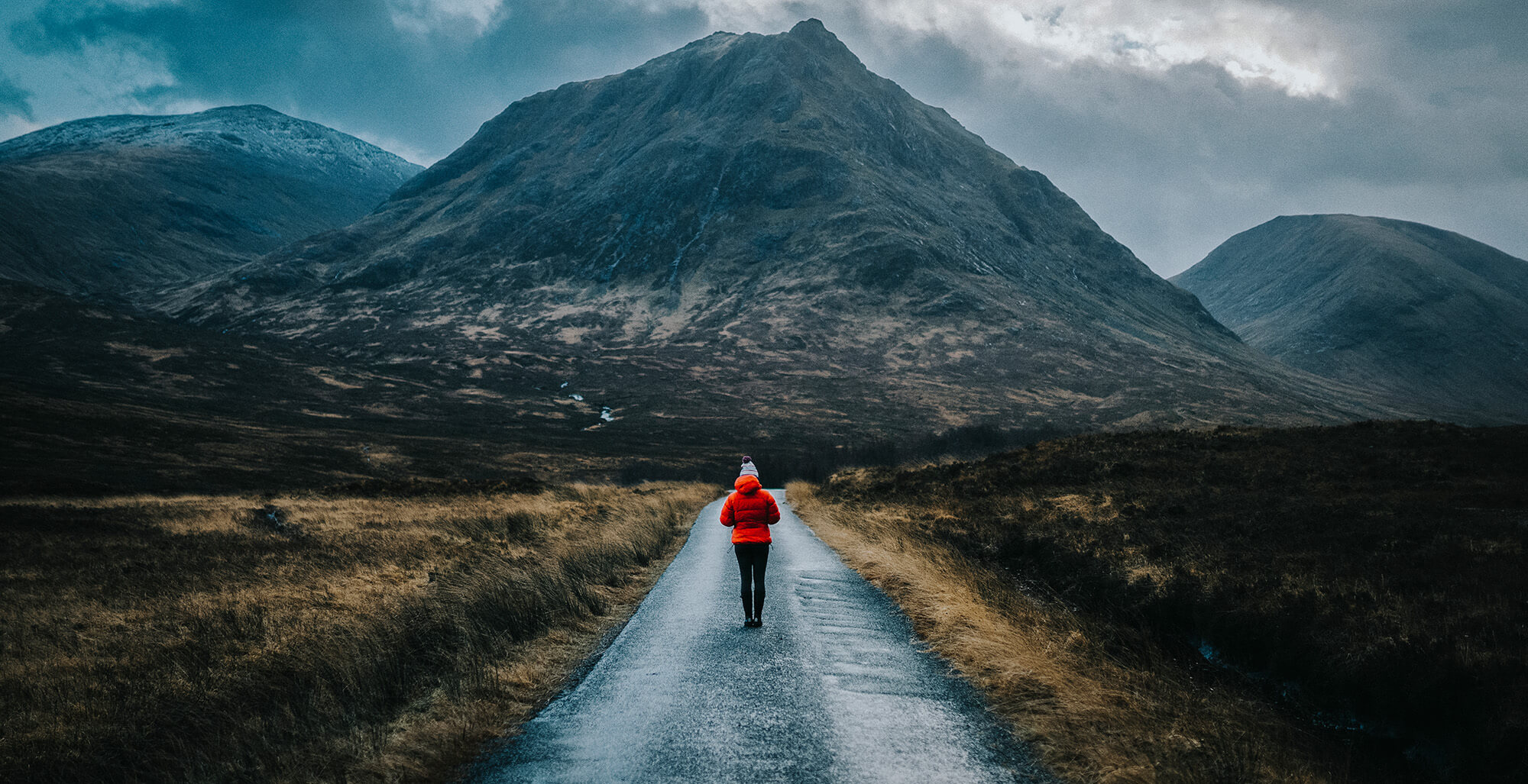 Woman walking down a road towards a mountain
