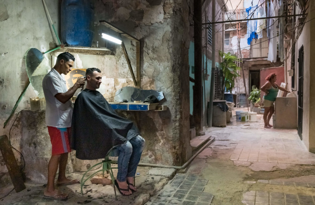 Barber giving a haircut in an alleyway in Havana