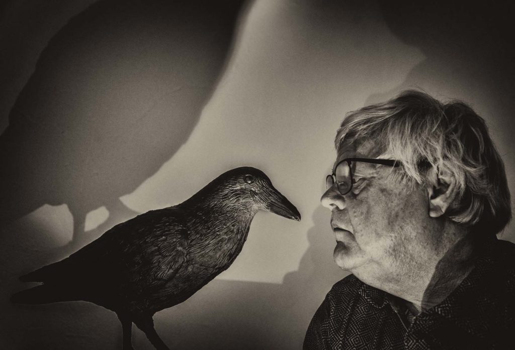 Man with glasses looking into the eyes of a stuffed bird