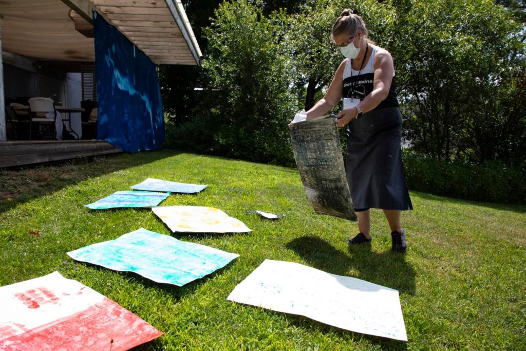 Student laying out painted paper to dry in the summer sun - Photo by Rafi Baeza