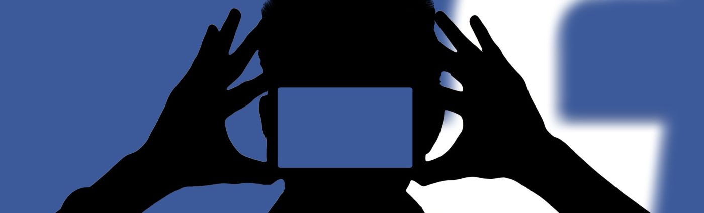 Silhouette of person taking a photo with Facebook icon in the background