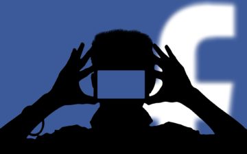 Silhouette of person taking a photo with Facebook icon in the background