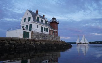 Early morning shot of the Rockland, Maine lighthouse with a windjammer in the background