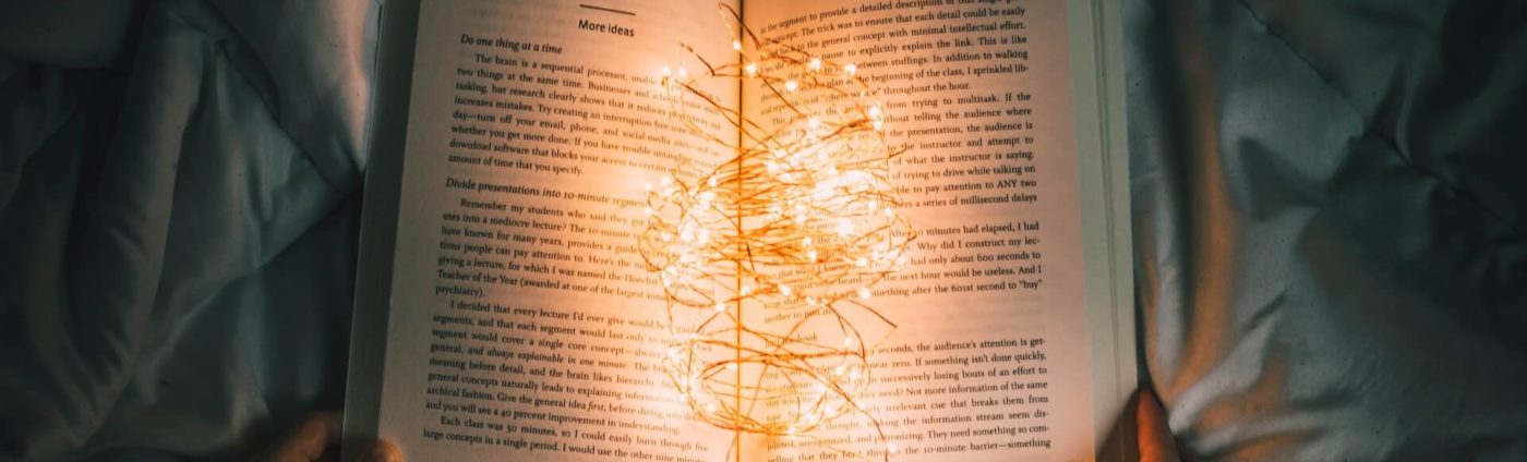 An open book with string of lights illuminating the pages