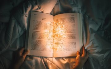 An open book with string of lights illuminating the pages