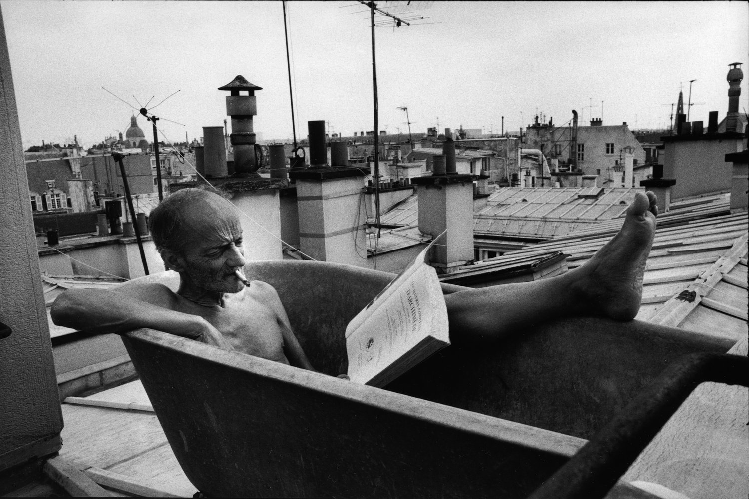 French man in an outdoor bathtub reading a book - Photo by Peter Turnley