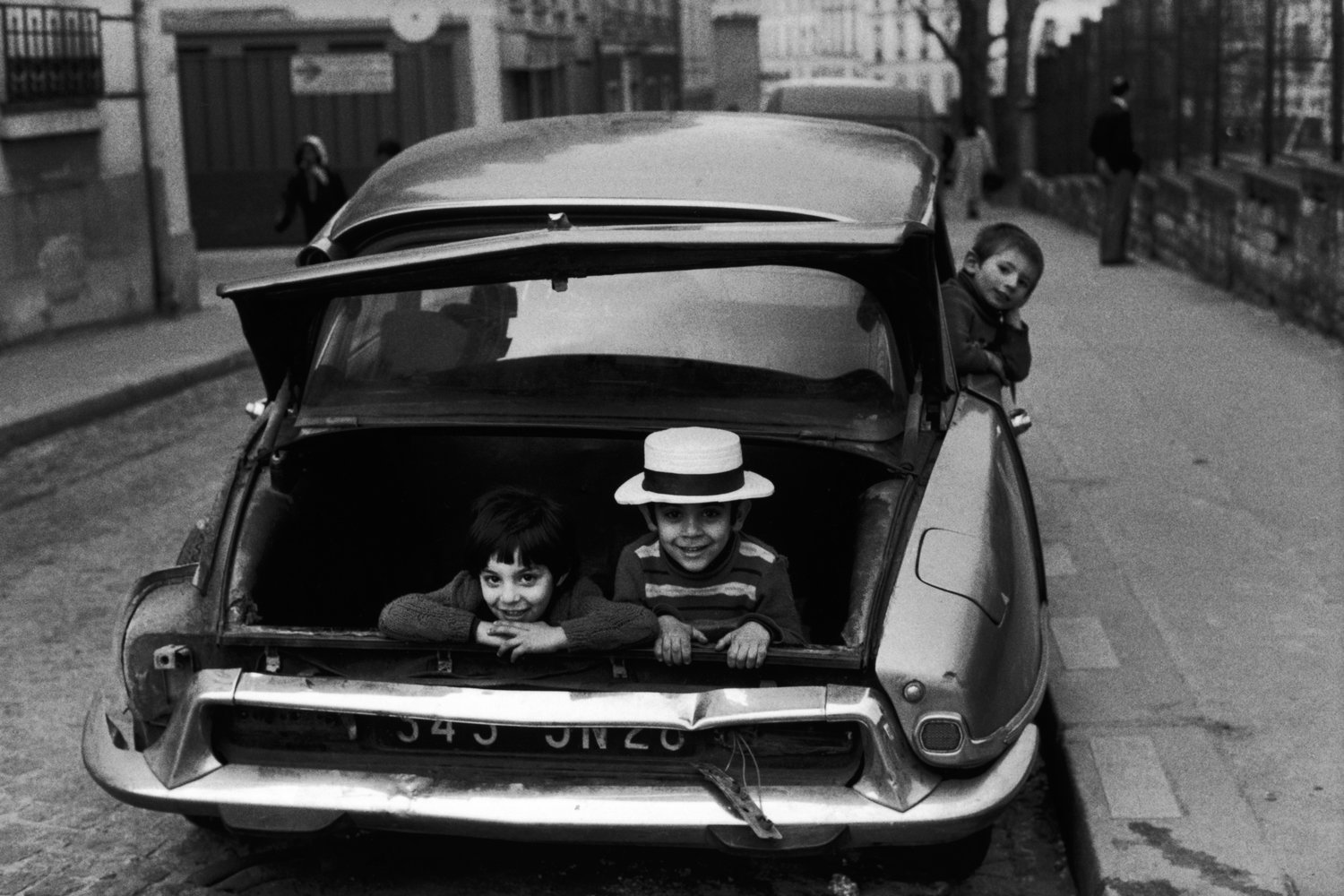 Children playing in trunk of an old car in Paris