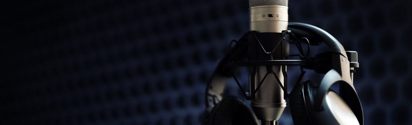 Studio microphone and headphones on mic stand against gray background