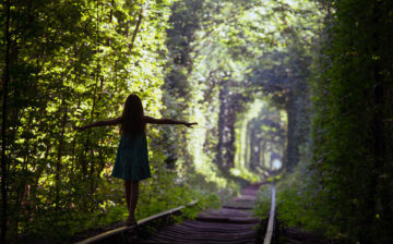 Girl balancing on old train tracks