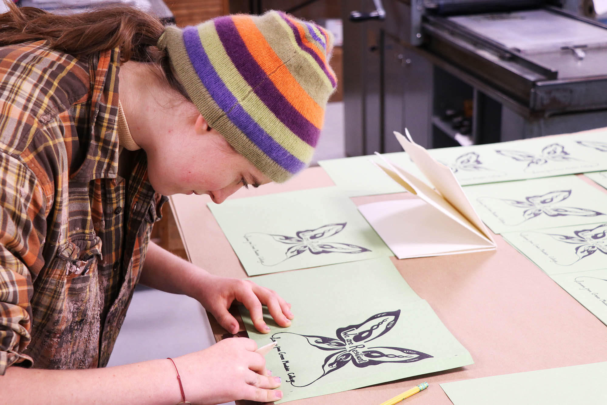 Book Arts & Design student focusing on their freshly printed letterpress design for a zine.