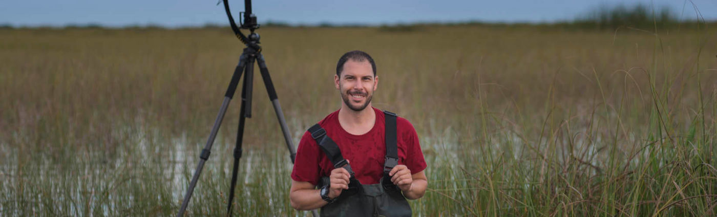 Matt Stock standing in a marsh with his camera set up