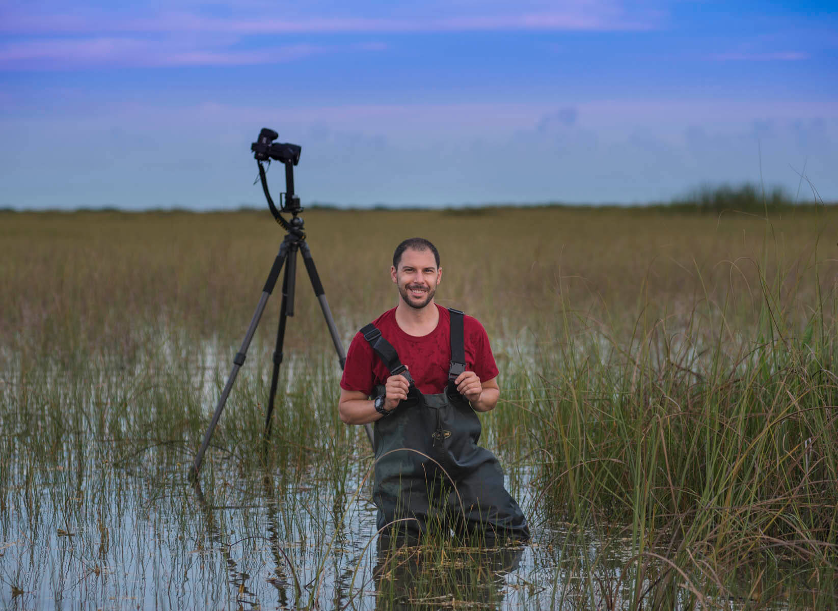 Matt Stock standing in a marsh with his camera set up