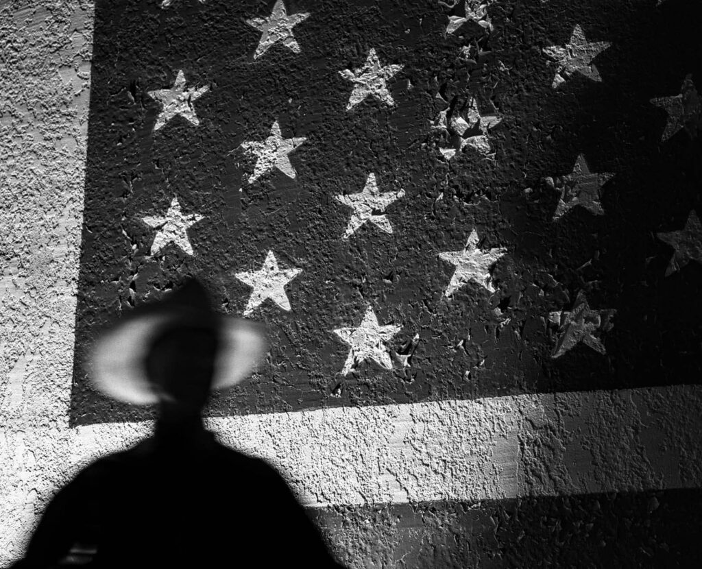 Photo by Steve Simon showing a shadow of a person over an American flag.