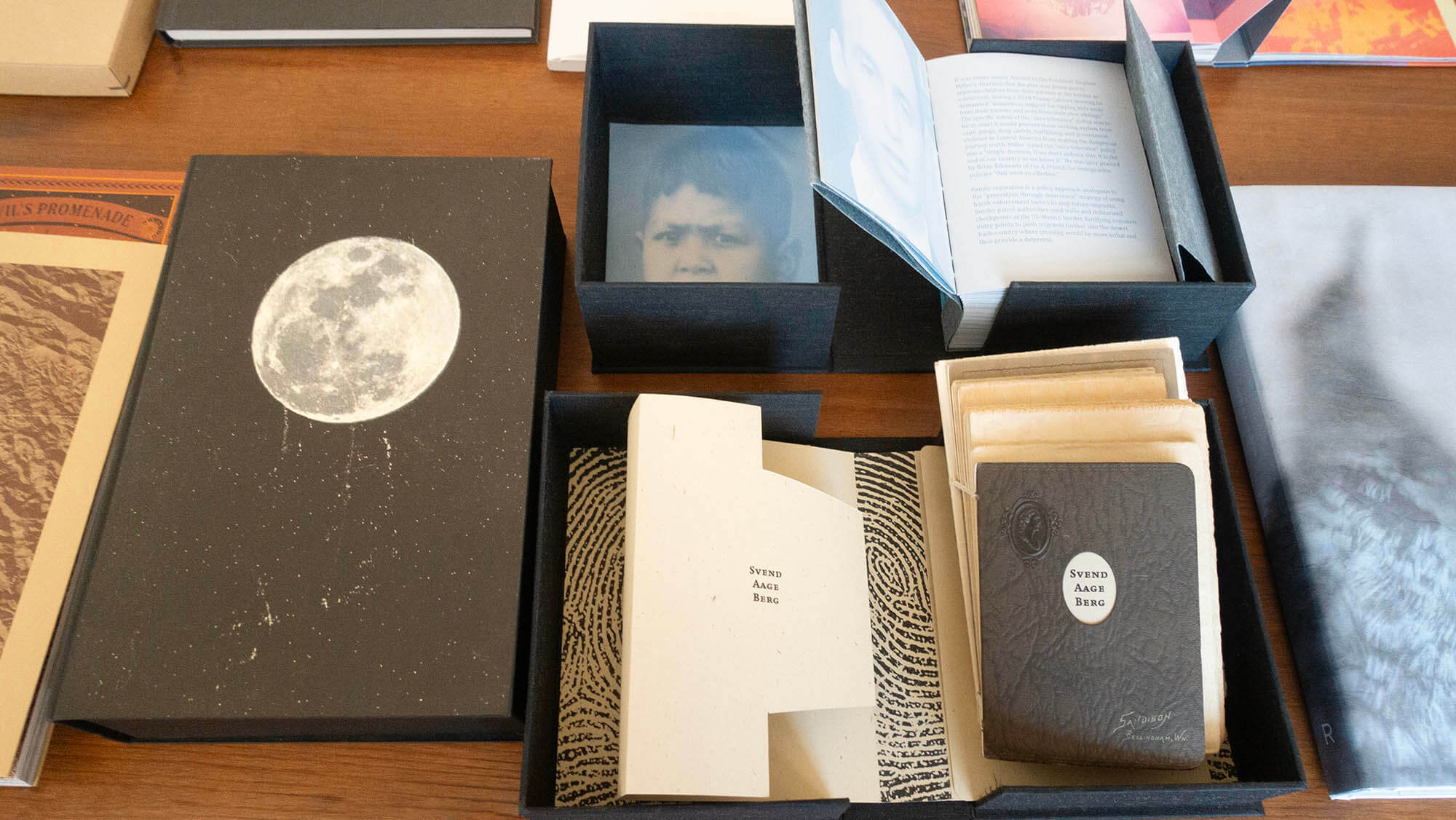 Center image, Lower row of books, clockwise from left: a. “DESIRE LINES” by Lara Shipley, Overlapse, 2023 b. “I’LL BE LOOKING AT THE MOON, BUT I’LL BE SEEING YOU” by Hari Katragadda and Shweta Upadhyah, ed. 500 c. Top: “JUST 545 KIDS” by Elsi Vassdal Ellis, hand-made artists’ book (variable ed. 15) d. Top: “JUST 245 KIDS”, below: “SVEND AAGE BERG” both by Else Vassdal Ellis e. “SENSE” by Ann Hamilton, Radius Books (2022).